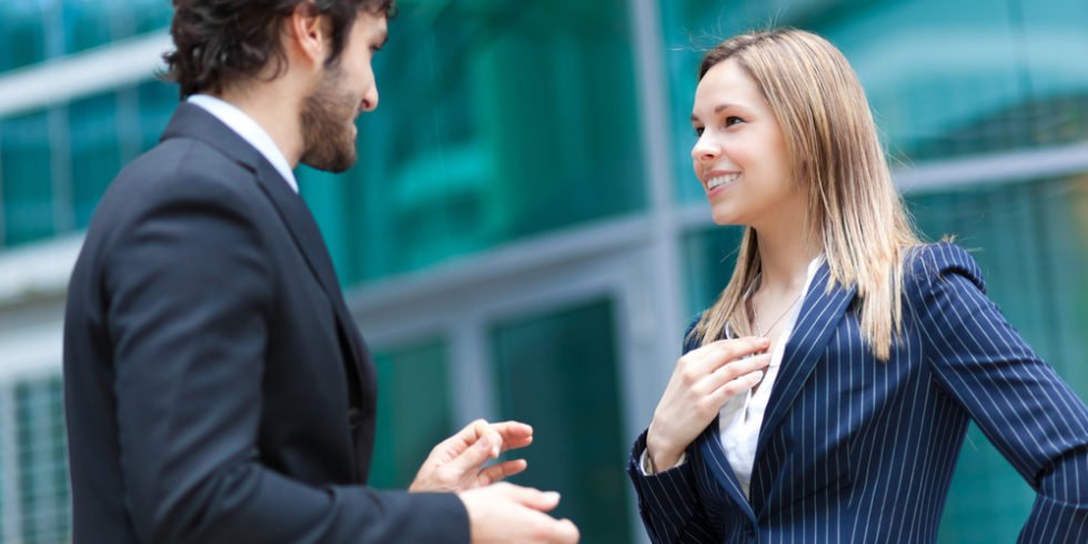 Mann und Frau im Businessoutfit stehen voreinander und sprechen