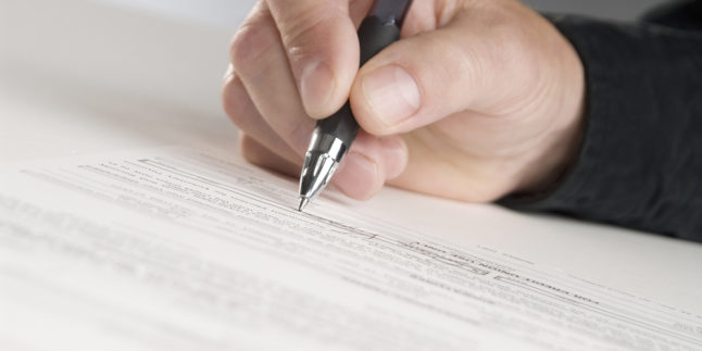 Hand mit Stift markiert einen Text