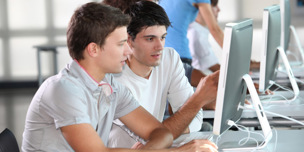 Zwei junge Männer diskutieren vor einem PC-Bildschirm