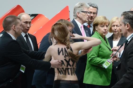 Eine Demonstrantin protestiert auf der Hannover Messe direkt vor dem russischen Präsidenten Wladimir Putin gegen die Menschenrechtsverletzungen in seinem Land. Budeszahlerin Angela Merkel hatte die junge Frau beim Eröffnungsrundgang erst gar nicht bemerkt.