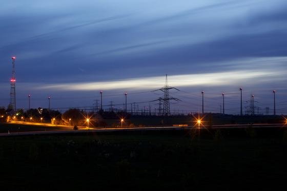 Eine Nachtaufnahme westlich von Berlin an der Autobahn A10 zeigt die 380-Kilovolt-Leitung (entspricht 380.000 Volt) und Windräder.