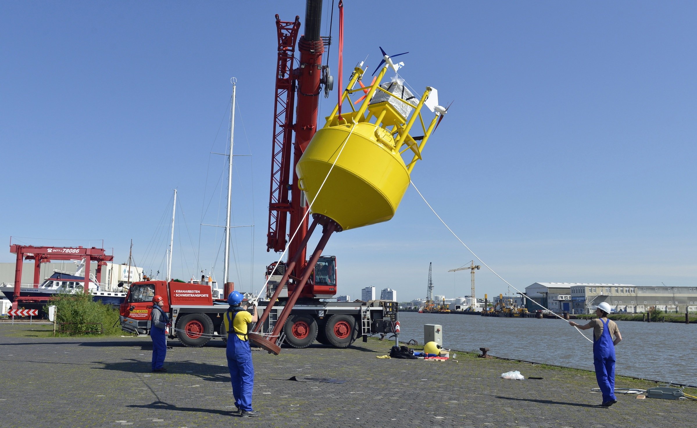 Mitarbeiter des Fraunhofer IWES richten in Bremerhaven die Boje an der Kaikante auf und setzen das Messgerät anschließend sicher ins Hafenbecken. Von Bremerhaven aus startete die Boje ihre Reise in Richtung des ersten deutschen Offshore-Windparks Alpha Ventus in der Nordsee.