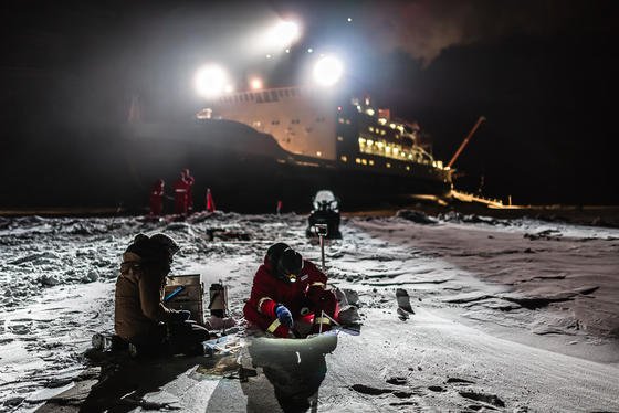 Die Forscher Steffi Arndt (l.) und Stephan Paul (r.) untersuchen die Eigenschaften des antarktischen Schnees im Scheinwerferlicht des deutschen Forschungsschiffes Polarstern.