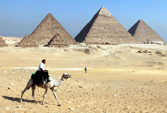 Ein ägyptischer Polizist auf einem Kamel reitet vor den Pyramiden von Gizeh. Aus einer Kammer der Cheops-Pyramide haben deutsche Amateur-Archäologen ohne Genehmigung Farbe von der Wand gekratzt. Das ägyptische Ministerium für Altertümer will sie deshalb international zur Fahndung ausschreiben.