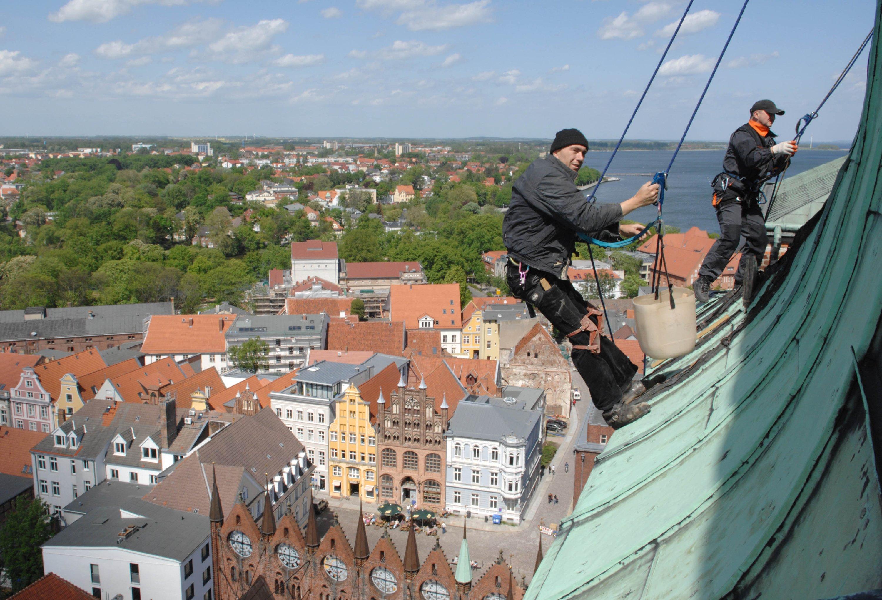 Industriekletterer auf dem Turm der Stralsunder Nikolaikirche. Sie brauchen meist mehrere Tage, um große Fassaden zu inspizieren. Die Drohne soll das in wenigen Stunden schaffen. 