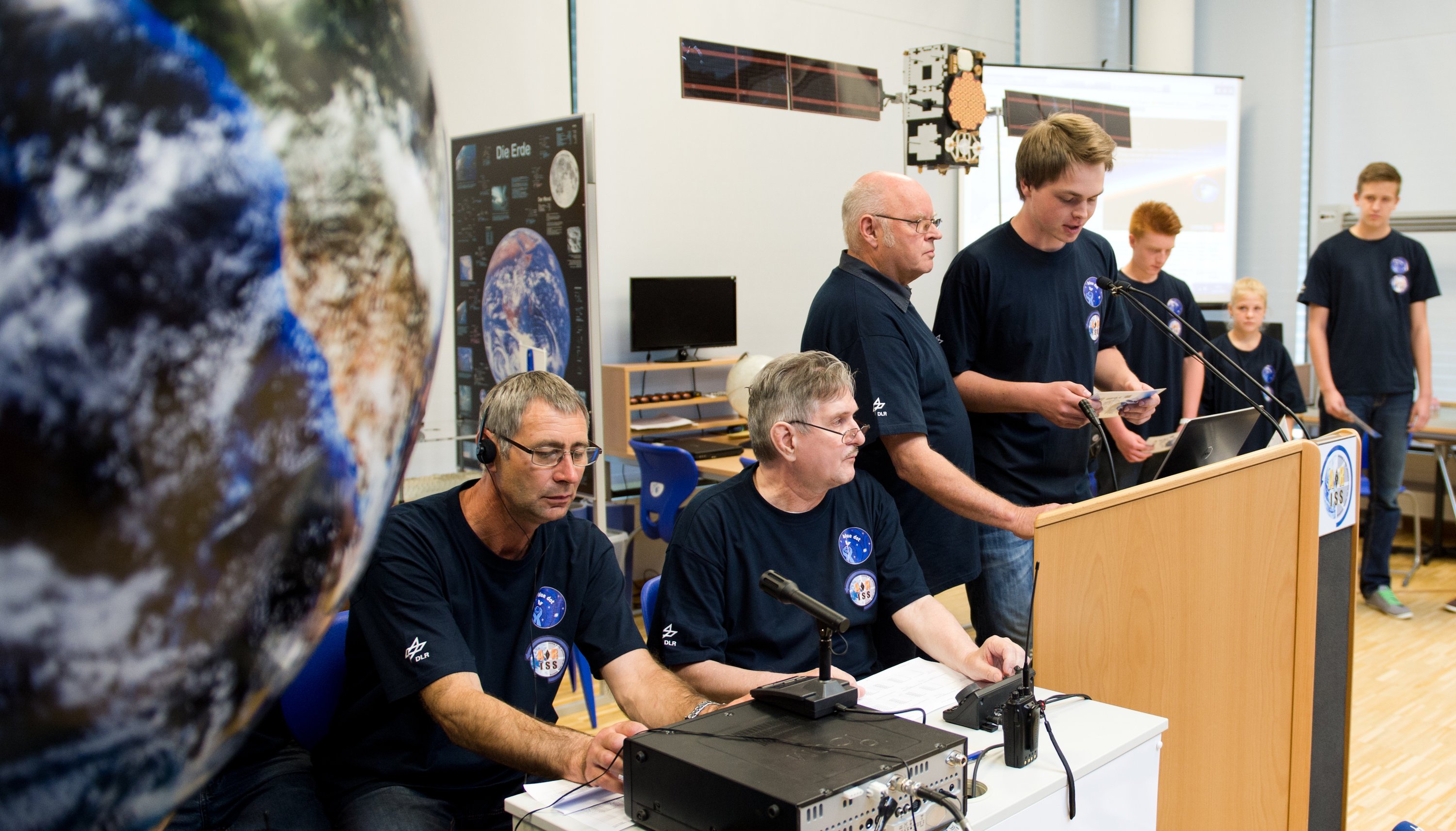 Alexander (17) nimmt zusammen mit Funkamateur Steffen Kröpf (li.), Wolfgang Andree (2.v.l.), Leiter des DLR-Project-Lab, und DLR-Mitarbeiter Ingo Goltz (3.v.l.), mit anderen Schülerinnen und Schülern aus Mecklenburg-Vorpommern am 2. Juli im Deutschen Zentrum für Luft- und Raumfahrt in Neustrelitz per Funk Kontakt mit der Internationalen Raumstation ISS und dem dort arbeitenden deutschen Astronauten Alexander Gerst auf. Während seiner für 166 Tage angesetzten Mission ist Gerst dabei in 100 verschiedene Experimente aller ISS-Partner eingebunden. 