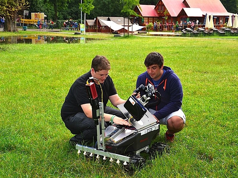 Die Studierenden Michael Schmidpeter (links) und Tim Schuler testen den radgetriebenen Suchroboter Simon auf einer Wiese in Nürnberg.