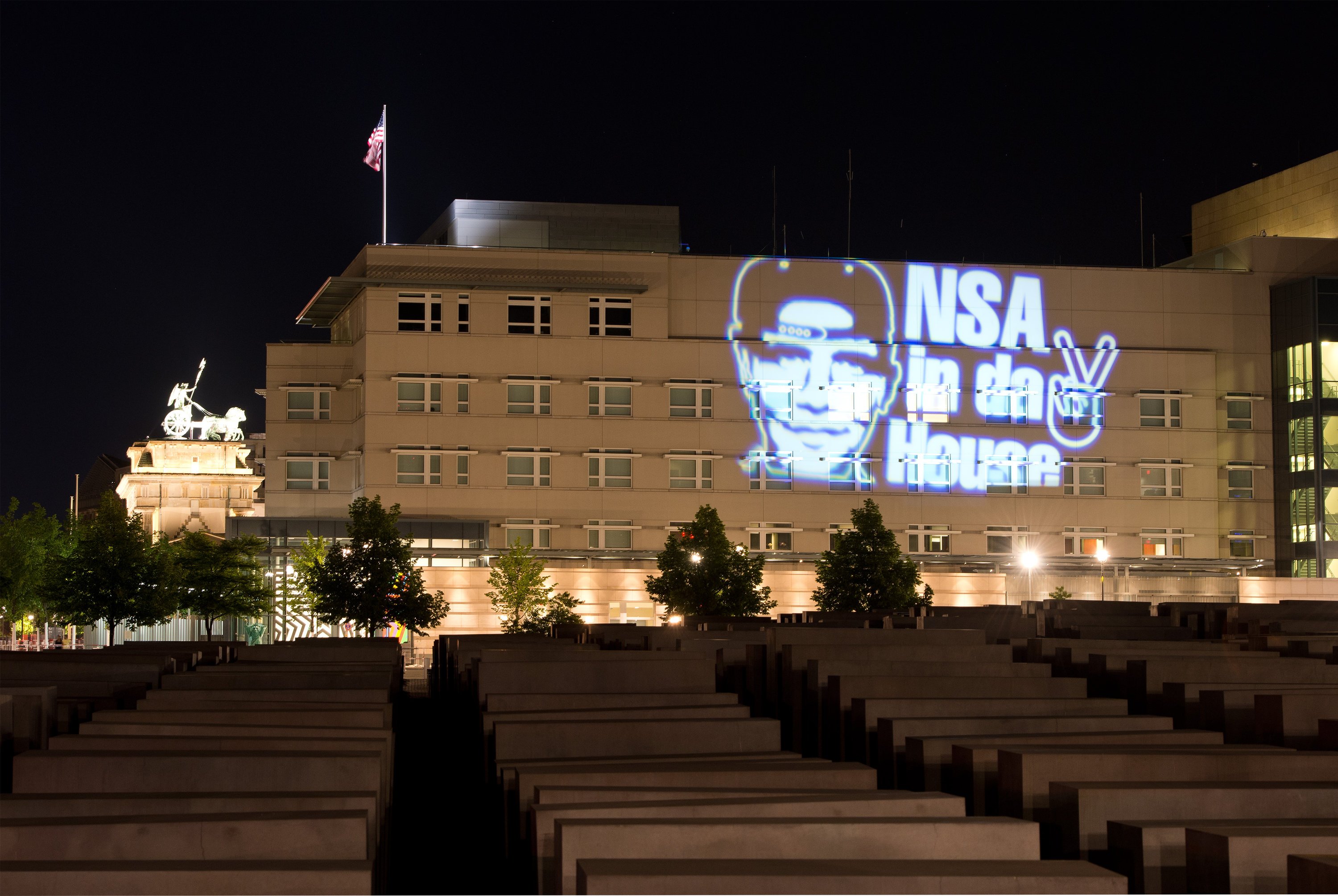 Den Schriftzug NSA in da House und das stilisierte Victory-Zeichen hat der Düsseldorfer Lichtkünstler Oliver Bienkowski im Juli 2014 auf die US-Botschaft in Berlin projiziert. Auch der US-Geheimdienst NSA soll Teil des Zusammenschlusses Five Eyes sein.