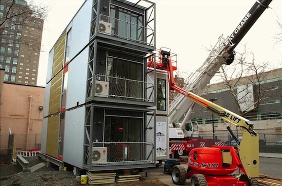 Kräne stapeln die Container aufeinander: Auf dem Dach ist eine Solaranlage für die Stromversorgung installiert. 