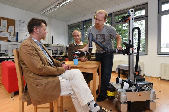 Benjamin Stähle (r.), Wissenschaftlicher Mitarbeiter an der Hochschule Ravensburg-Weingarten, bereitet im Forschungslabor den Serviceroboter Marvin vor. Er soll sein Können Maik Hans-Joachim Winter (l.), Professor für Pflegewissenschaft, und Wolfgang Ertel, Professor für Informatik, demonstrieren.