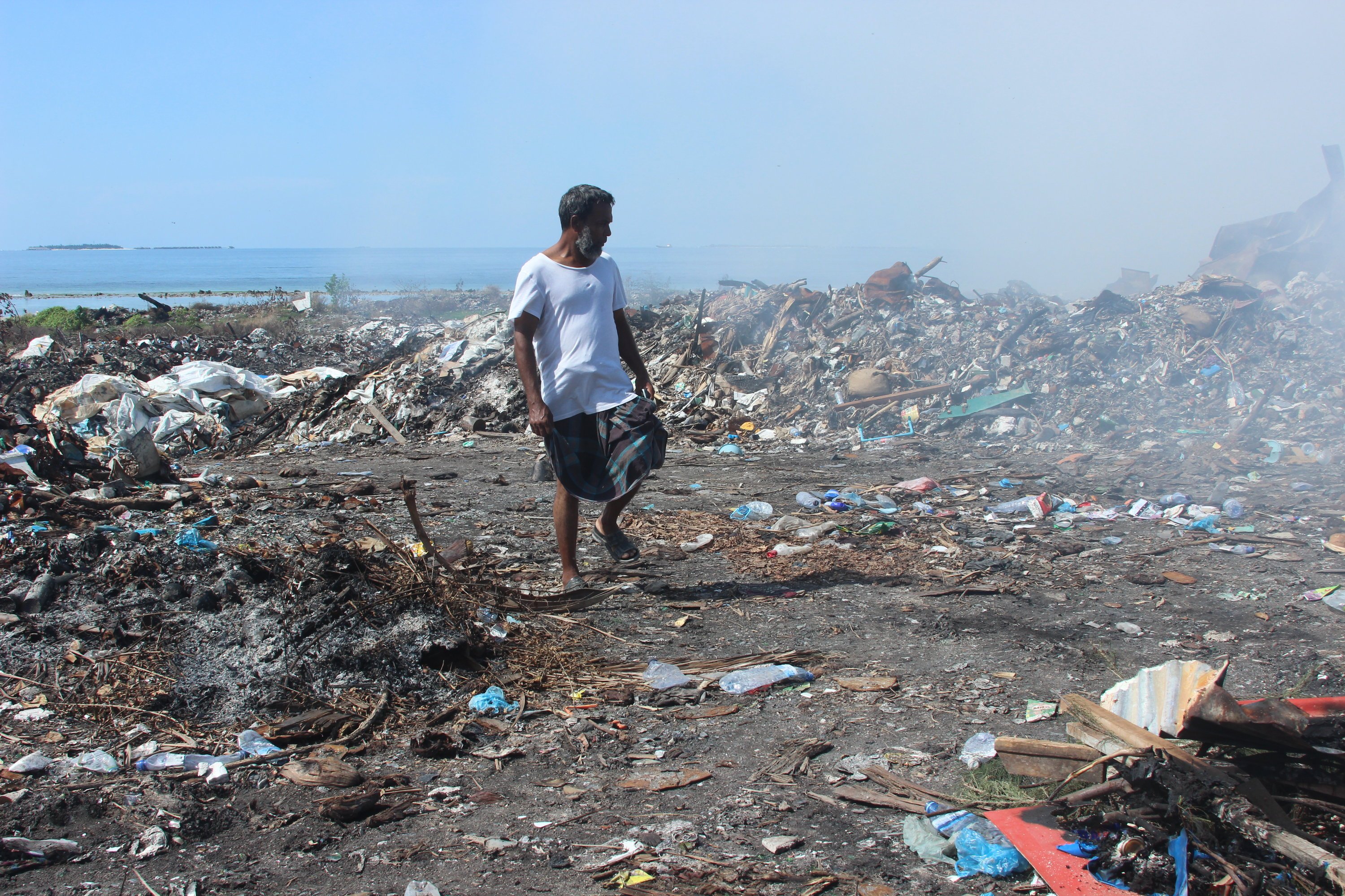 Der Gastarbeiter Khaled aus Bangladesch läuft durch schwelende Abfallreste am 21. März 2014 auf der Müllinsel Tilafushi, Malediven. Die Malediven-Insel war einst eine türkisblaue Lagune im Indischen Ozean, bis die Regierung in den 90er Jahren beschloss, dort einen Großteil des Mülls des Landes abzuladen. 