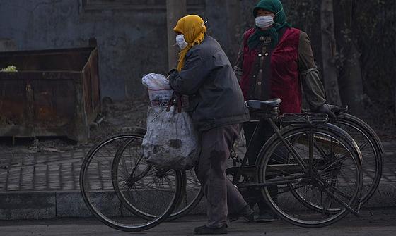 Radfahrer mit Atemmaske in Peking: Ein Teil der hohen Luftverschmutzung in China geht auf die Billigproduktion der Exportindustrie für westliche Länder zurück, so eine Studie der Universität Peking. Inzwischen verwehen die Luftschadstoffe aus China so weit, dass sie bereits die Westküste der USA erreicht haben.