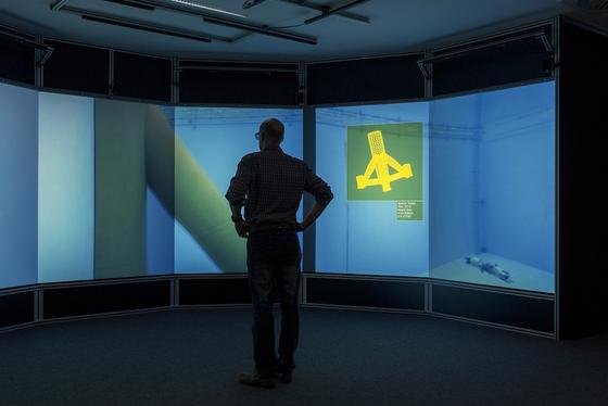DFKI-Forscher steuern das Unterwasserfahrzeug Seabotix durch das Testbecken. Dort macht es Filmaufnahmen, die live in das Virtual Reality Labor – eine 3D-Testumgebung – übertragen werden. 