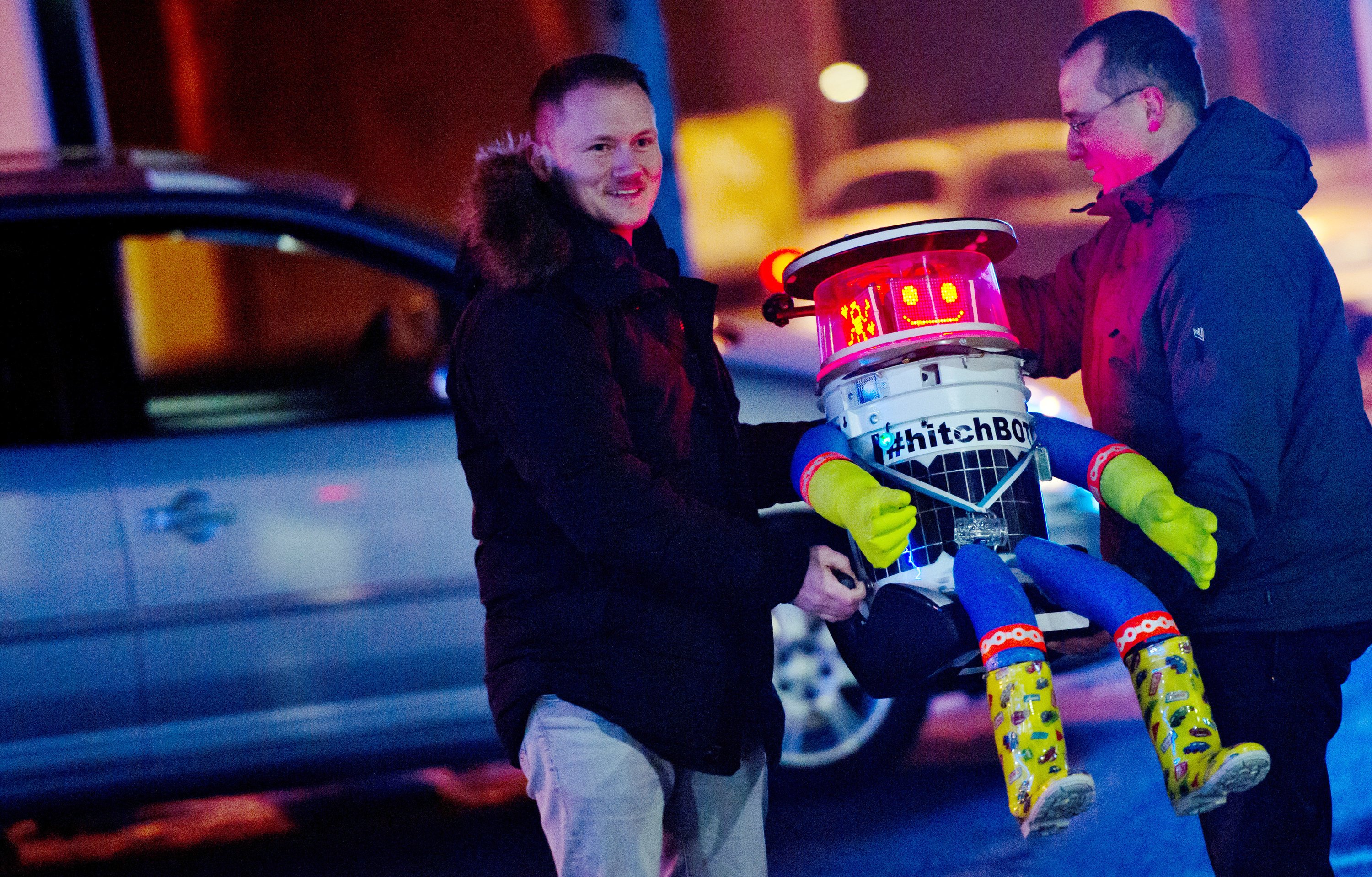 Martin (li.) und Bernd laden hitchBOT am 13. Februar in München in ihr Auto ein. Von dort aus startete der trampende Roboter eine zehntägige Tour durch Deutschland. Im Sommer 2014 hatte die Maschine per Anhalter bereits gut 6000 Kilometer durch Kanada zurückgelegt. 