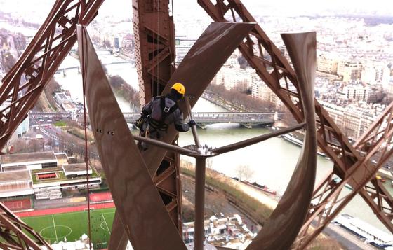 In 127 Metern Höhe installiert ein Arbeiter eine von zwei Windturbinen, die in der Farbe des Eiffelturms angestrichen und somit nahezu unsichtbar sind. Sie sind leistungsstark genug, um mehrere Restaurants und Souvenirläden mit Strom zu versorgen. 