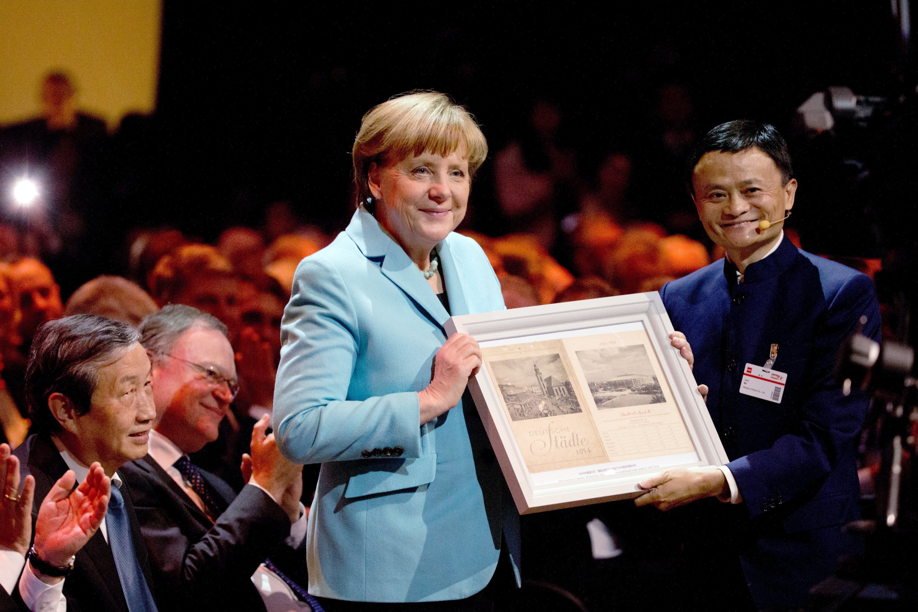 Jack Ma (re.), Gründer und CEO des Internetkonzerns Alibaba Group, überreicht Bundeskanzlerin Angela Merkel am 15. März 2015 während der Eröffnung der weltweit größten Computermesse CeBIT ein Geschenk neben Chinas Vize-Ministerpräsident Ma Kai (li.) und Stephan Weil (SPD), Ministerpräsident von Niedersachsen. F