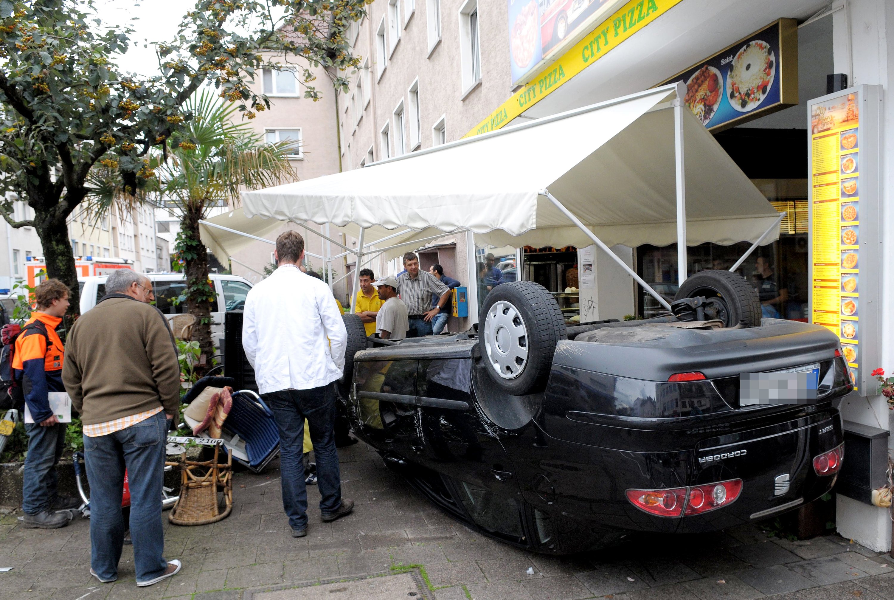 Ein umgekipptes Auto im Zelt einer Pizzeria in Darmstadt: Wie soll sich die Steuerungstechnik autonom fahrender Autos im Fall eines Unfalls mit verschiedenen Handlungsmöglichkeiten entscheiden? Ist der Crash mit einem Auto der Kollision mit Fußgängern vorzuziehen? Damit beschäftigen sich derzeit Forscher in Großbritannien und Deutschland.