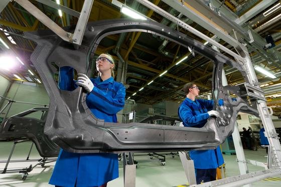 Eine Frau und ein Mann bereiten im BMW-Werk Landshut ein CFK-Karosserieteil für die Endbearbeitung durch Wasserstrahlschneiden vor: BMW setzt sich zum Ziel, dass der Frauenanteil im gesamten Konzern auf 17 % steigt.