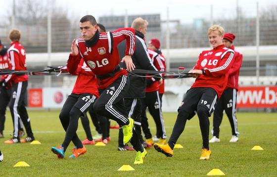 Die Spieler Kyriakos Papadopoulos (vorne) und Julian Brandt auf dem Trainingsplatz von Bayer Leverkusen, der direkt am Leverkusener Autobahnkreuz liegt (im Hintergrund): Eine Studie zeigt, dass eine erhöhte Feinstaubbelastung die Leistung von Fußballprofis beeinflussen kann.