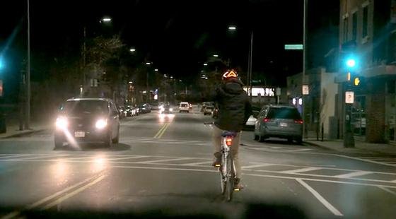 Abbiegen mit dem Lumos-Fahrradhelm: Die ausgestreckte linke Hand des Radfahrers ist kaum zu sehen, sehr wohl aber das Blinklicht, das nach links zeigt.