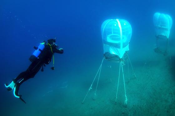 Die Prototypen der kleinen Gewächshäuser sind 6 bis 8 m unter der Wasseroberfläche am Meeresboden verankert. Die Pflanzen sollen angeblich doppelt so schnell wachsen wie an Land.