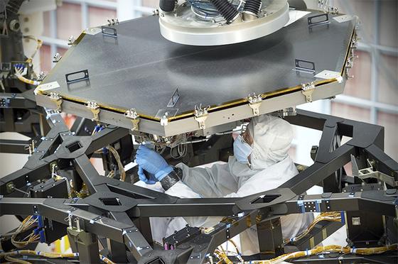Ein Ingenieur des Nasa Goddard Space Flight Centers installiert den ersten Spiegel des James Webb Space Telescopes auf der Trägerstruktur.
