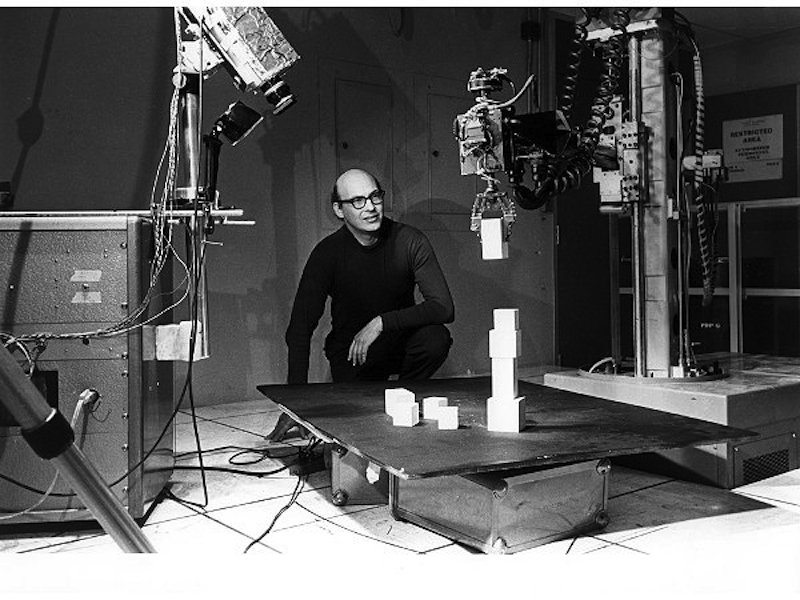 Marvin Minsky mit seinem berühmten Roboterarm Ende der 1960er/Anfang der 1970er Jahre: Dieser Arm verfügte über eine Videokamera und wurde von einem Computer gesteuert. Bei diesem Experiment baut der Minsky-Arm mit Bauklötzen einen Turm.