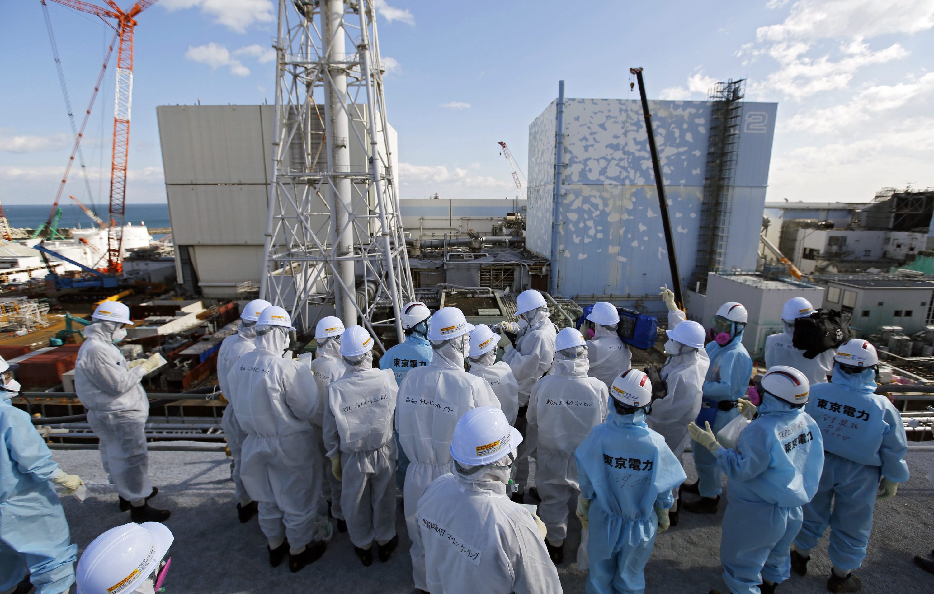 Mit Schutzanzügen und Masken ausgerüstet verschaffen sich Pressevertreter aus aller Welt am 10. Februar 2016 in Fukushima auf dem Reaktorgelände einen Überblick über den Stand der Arbeiten knapp fünf Jahre nach der Katastrophe. Die Betreibergesellschaft Tepco will den Rückbau in 40 Jahren schaffen.