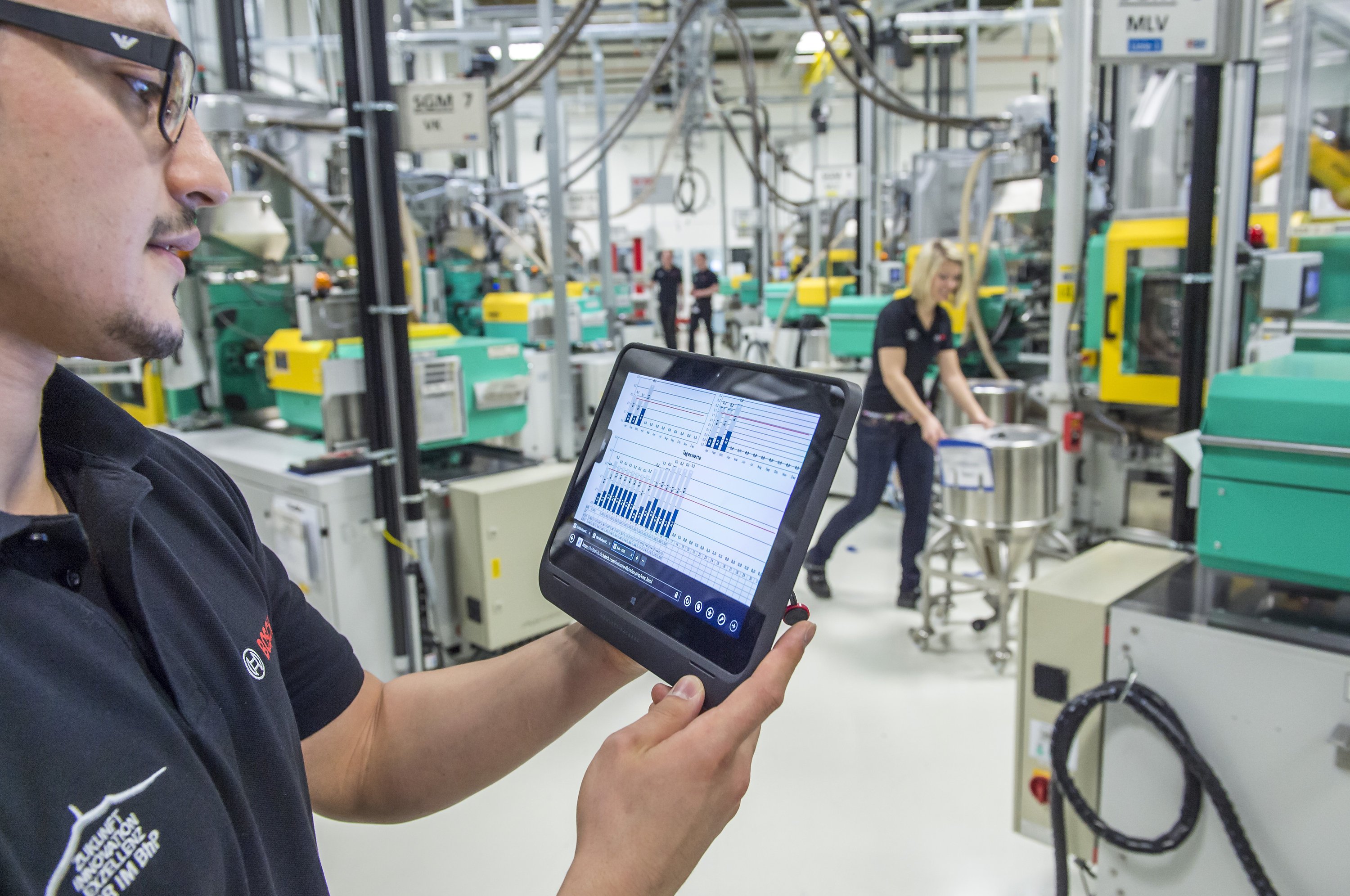 Bosch-Mitarbeiter ruft über ein Tablet die Betriebsdaten vernetzter Maschinen für Metallspritzguss ab: Die intelligente Vernetzung von Maschinen und Produkten führt nach einer McKinsey-Studie zu höherer Produktivität, mehr Energieeffizienz und sichereren Arbeitsplätzen. Das würde sich ab 2025 in einem weltweiten Mehrwert von 3,7 Billionen $ pro Jahr niederschlagen.