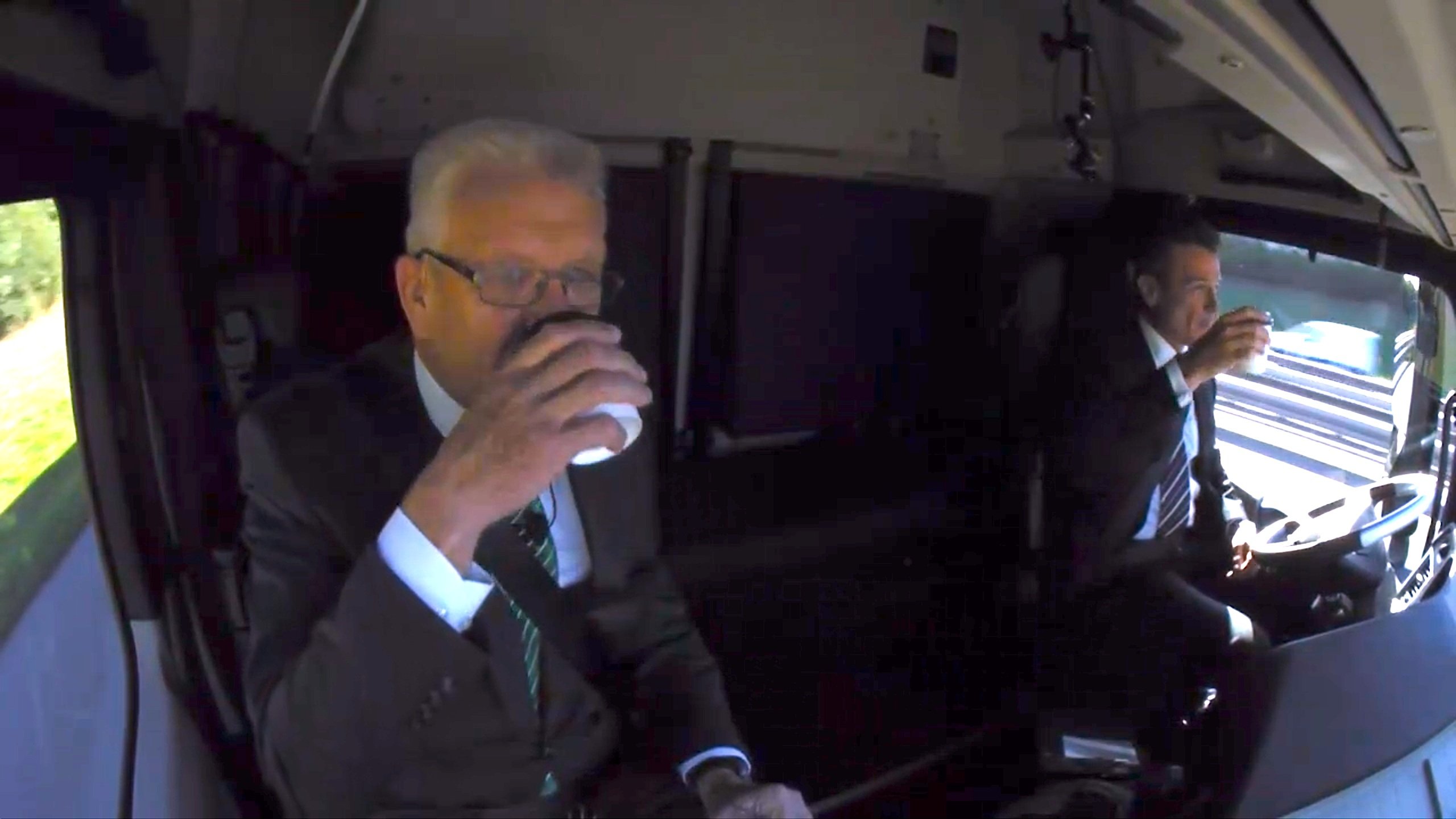 Daimler-Truck-Chef Wolfgang Bernhard und Ministerpräsident Winfried Kretschmann beim Kaffeetrinken, während der Actros selbstständig über die A8 steuert.