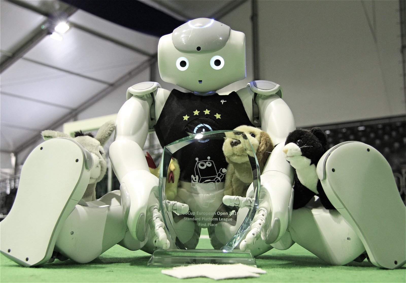 NAO-Roboter des Teams B-Human mit Sieger-Pokal.