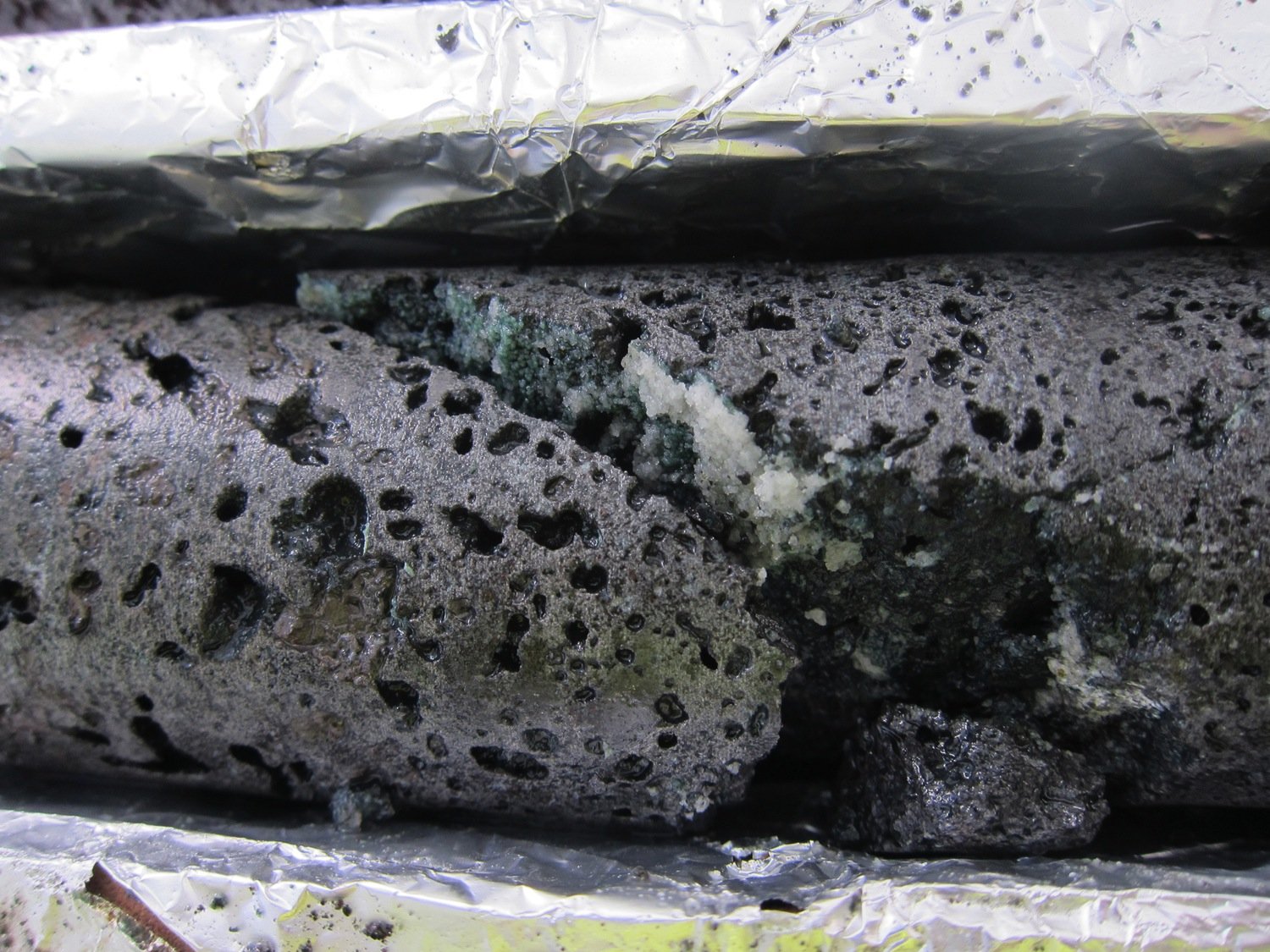Weiße Adern aus Karbonatgestein durchziehen der porösen Basalt aus der Tiefe. 