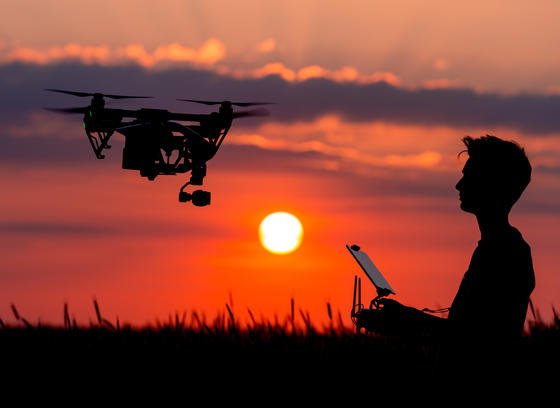 Sieht idylisch aus: Ein Junge sitzt auf einem Feld in Brandenburg und steuert bei Sonnenuntergang eine Drohne. Doch wie sollen kommerzielle Flüge mit Lieferdrohnen gesetzlich geregelt werden. Wie kann Sicherheit garantiert werden, wenn der Pilot das Fluggerät nicht mehr sehen kann? Und mehrere Drohnen gleichzeitig steuert? Amazon testet jetzt in Großbritannien solche Flüge.  