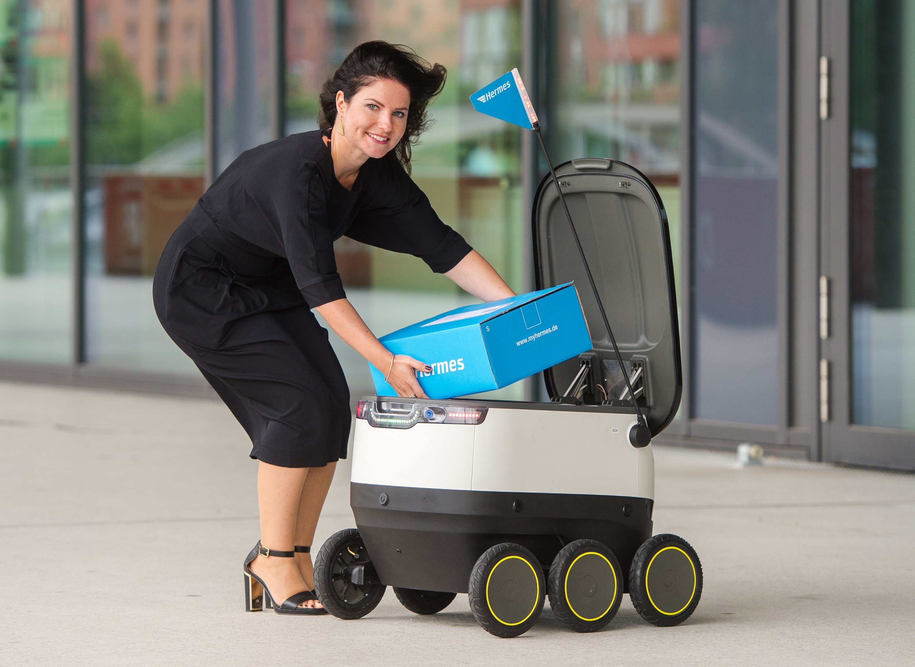 Daniela Kirchner von dem Paketlieferanten Hermes belädt in Hamburg einen von der Firma Starships Technologies entwickelten Roboter.