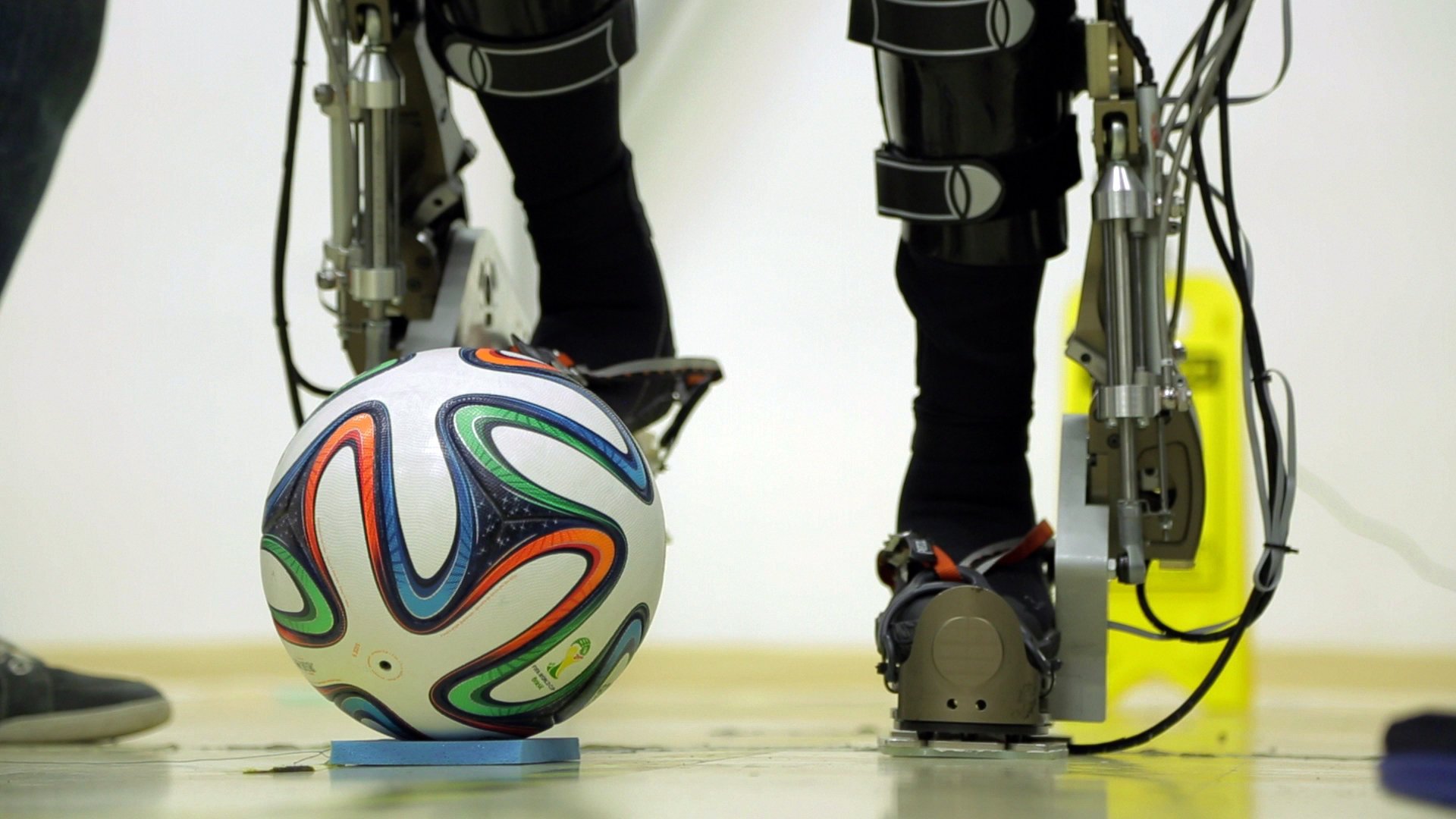 Eine Testperson kickt mit einem Spezial-Roboteranzug gegen den WM-Ball Brazuca. Der symbolische Anstoß zur Fußball-WM in São Paulo am 12. Juni 2014 war eine ganz besondere Premiere für einen brasilianischen Rollstuhlfahrer. Der querschnittgelähmte Patient schoss den Ball mit Hilfe eines Exoskeletts vom Spielfeldrand auf das Feld. Die Demonstration war Teil des internationalen Projektes Walk Again, an dem 156 Forscher, Ingenieure und Techniker unter Regie des brasilianischen Neurowissenschaftlers Miguel Nicolelis beteiligt sind.