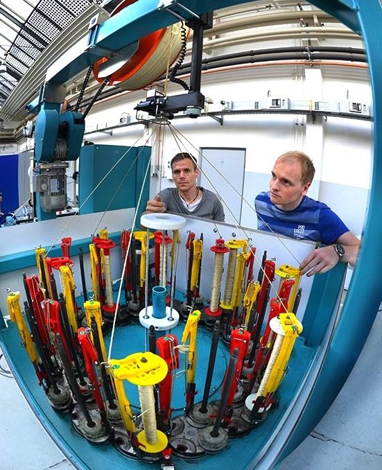 Ingo Berbig (l.) und Dirk Fischer bereiten an einer Flechtmaschine die Herstellung der textilen Speichen aus Hightech-Fasern vor.