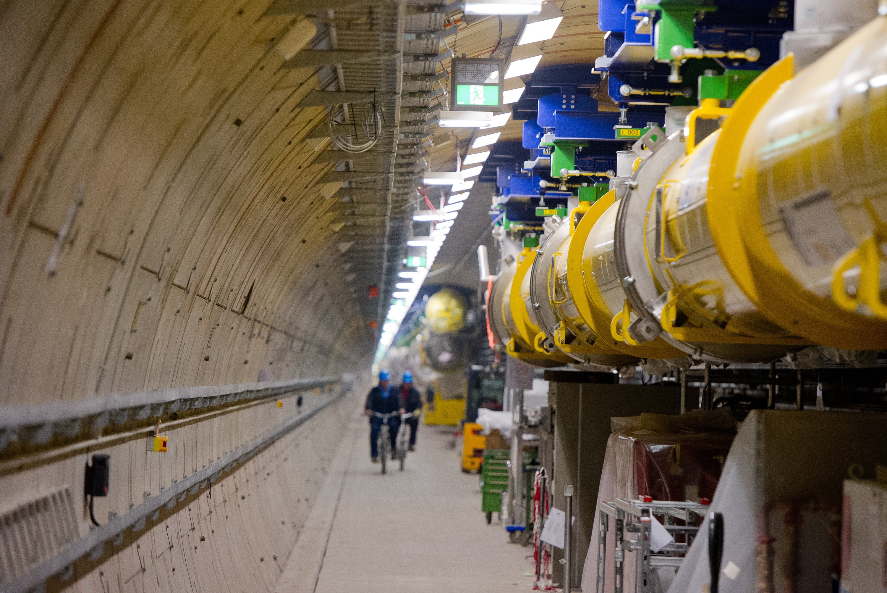 Mitarbeiter fahren in Hamburg im Teilchenbeschleuniger-Tunnel des Röntgenlasers European XFEL am Beschleuniger (gelb) entlang. 