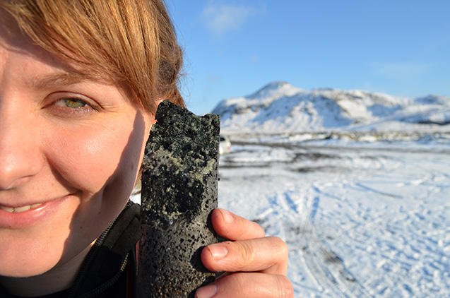 Forscherin Sandra Snaebjornsdottir zeigt einen Basaltstein, in dem CO2 zu Karbonat (weiß) mineralisiert ist. Die Umwandlung dauert weniger als zwei Jahre, nicht wie bislang angenommen hunderte bis tausende von Jahren. 