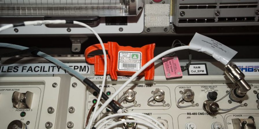 Im Inneren des orangenen Päckchens befinden sich hunderte von kleinen Detektoren, die im Forschungslabor Columbus der ISS die Strahlung erfassen. 11 solcher Detektoren-Sets sind jetzt installiert und messen sechs Monate lang die Belastung durch kosmische Strahlung. Das Deutsche Zentrum für Luft- und Raumfahrt (DLR) leitet das Experiment Dosis 3D.