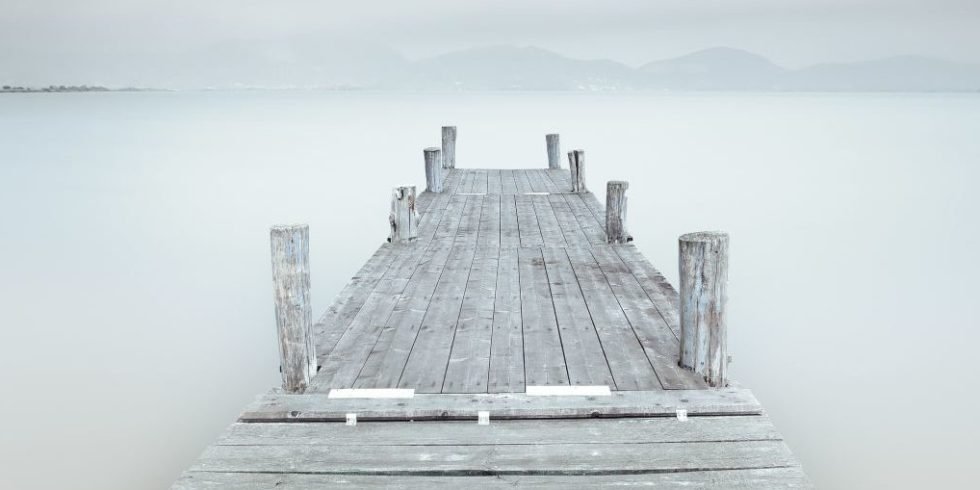 Grauer Steg über einem von Nebel bedeckten See