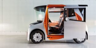 Ein weißes Auto mit geöffneter Schiebetür und hoher Frontscheibe