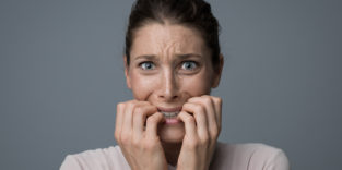 junge Frau, die verzweifelt auf ihren Fingernägeln kaut