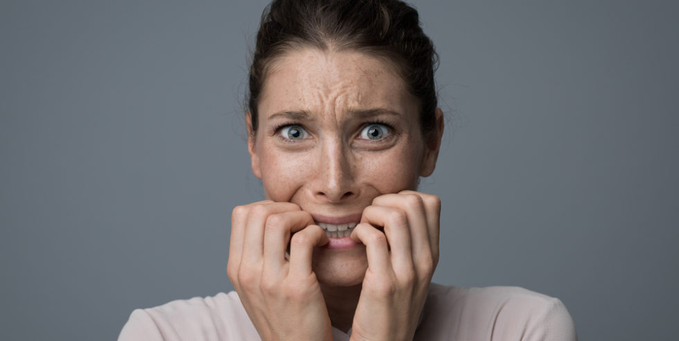 junge Frau, die verzweifelt auf ihren Fingernägeln kaut