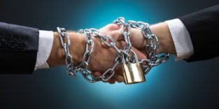 Zwei Hände beim Handschlag werden von einer dicken Eisenkette mit Schloss festgehalten