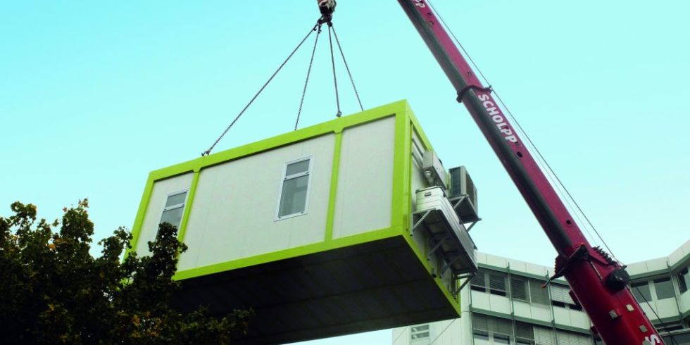 Ein Container, in dem sich die mobile Fabrik befindet, wird per Kran an seine Einsatzstelle befördert.