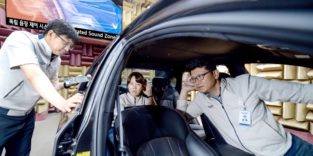 Drei Kia-Mitarbeiter sitzen in einem Auto und lauschen