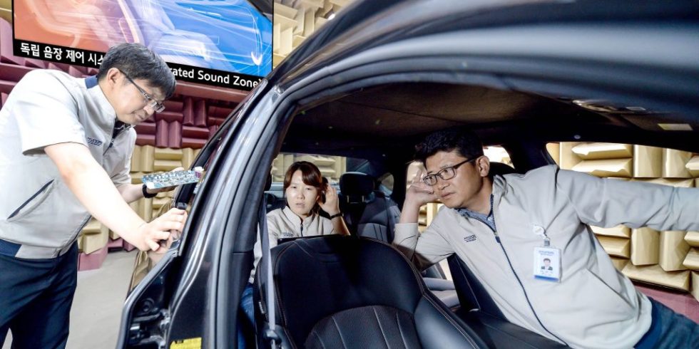 Drei Kia-Mitarbeiter sitzen in einem Auto und lauschen