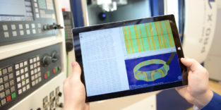 Zwei Hände halten ein Tablet, auf dem ein CAD-Programm zu sehen ist.