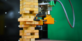 Industrieroboter greift Holzklötzchen beim Jenga-Spiel