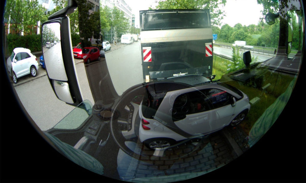 Simulierter Blick aus dem Fahrerhaus eines Lkw. Die Kameraaufnahme überlagert sich mit der Fahrerperspektive. Vorm Fahrzeug ist ein Pkw erkennbar, als wäre der Lkw transparent.
Foto: Fraunhofer IOSB